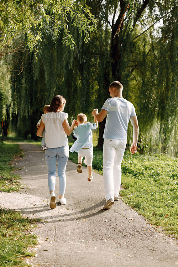 back view photo of a family walking in a park on summer